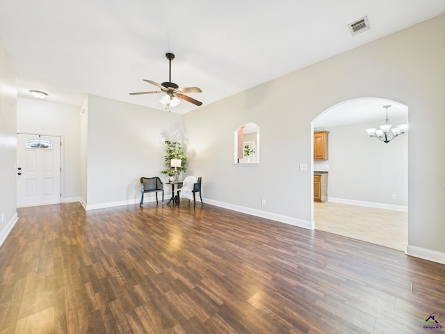 empty room featuring visible vents, ceiling fan with notable chandelier, wood finished floors, arched walkways, and baseboards