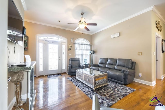 living area with crown molding, baseboards, and wood finished floors