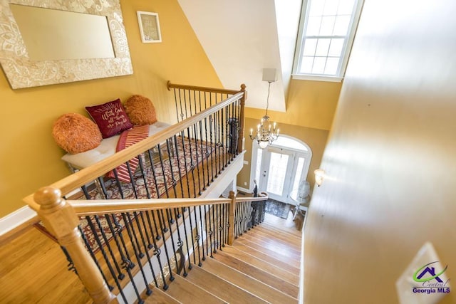 stairs with baseboards, an inviting chandelier, and wood finished floors