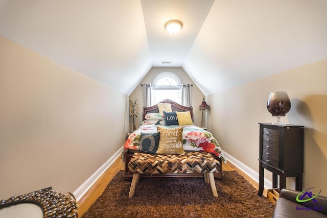 bedroom featuring vaulted ceiling, baseboards, visible vents, and wood finished floors