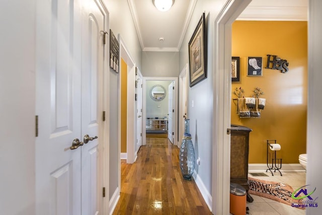 hall featuring crown molding, wood finished floors, and baseboards