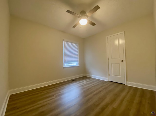 unfurnished room with a ceiling fan, dark wood-style floors, and baseboards