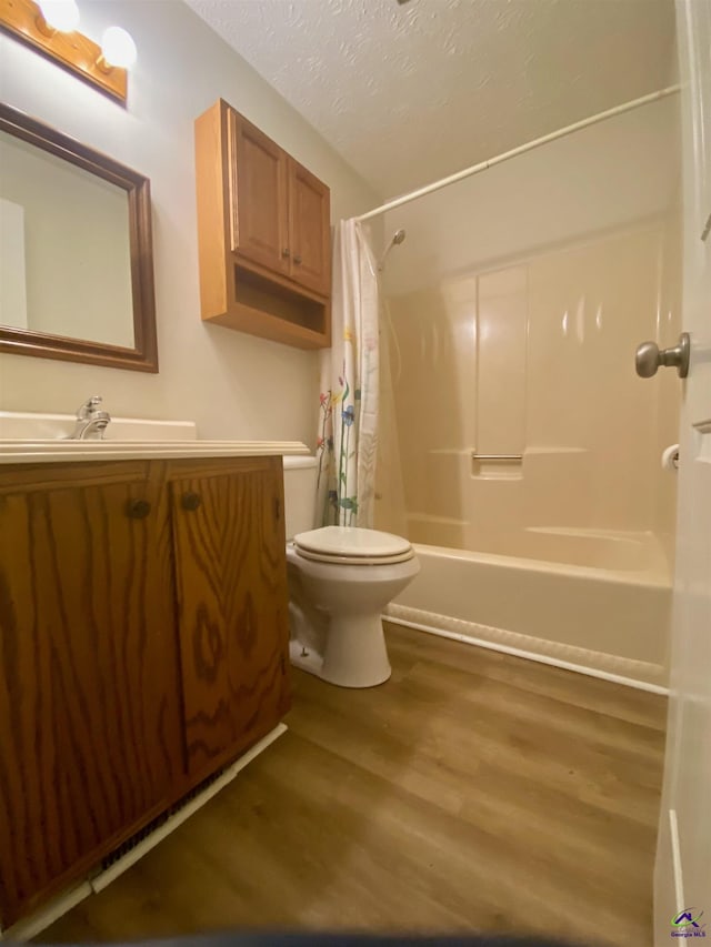 full bathroom featuring vanity, wood finished floors, a textured ceiling, toilet, and shower / tub combo with curtain