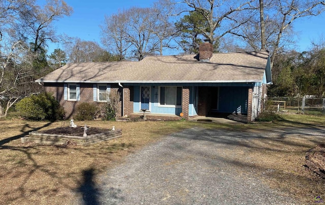 ranch-style home with driveway, brick siding, a chimney, and fence