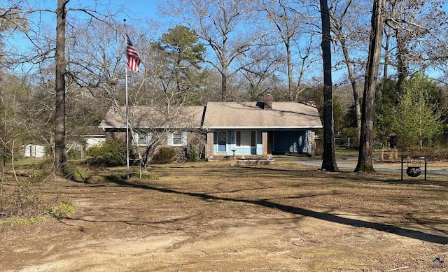 view of front of house featuring a chimney and dirt driveway