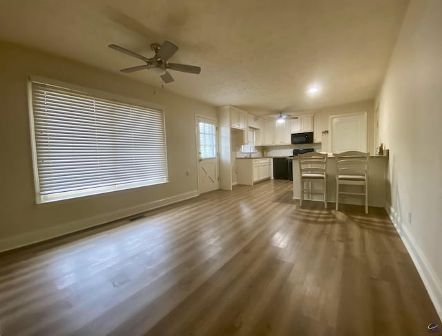 unfurnished living room featuring ceiling fan, baseboards, and dark wood-style flooring