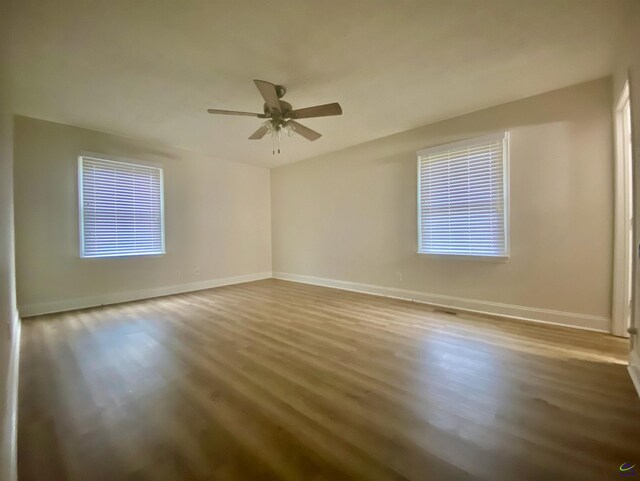 empty room with baseboards, wood finished floors, and a ceiling fan