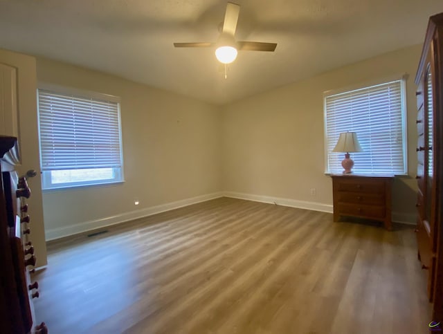 unfurnished bedroom featuring visible vents, wood finished floors, baseboards, and ceiling fan