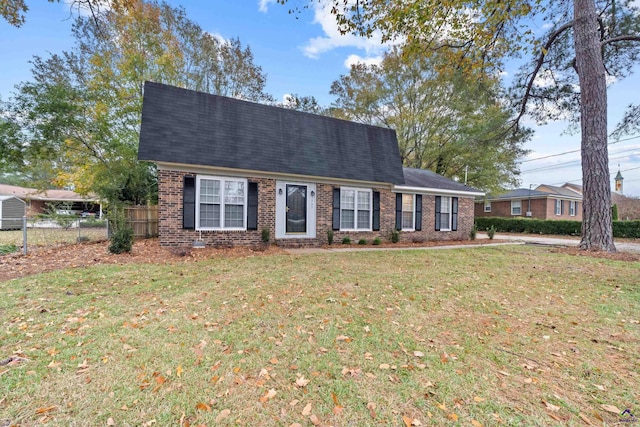 dutch colonial with brick siding, roof with shingles, a front lawn, and fence