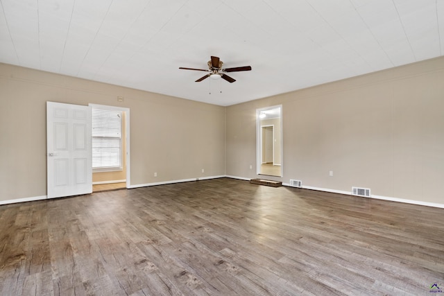 empty room featuring baseboards, wood finished floors, visible vents, and ceiling fan