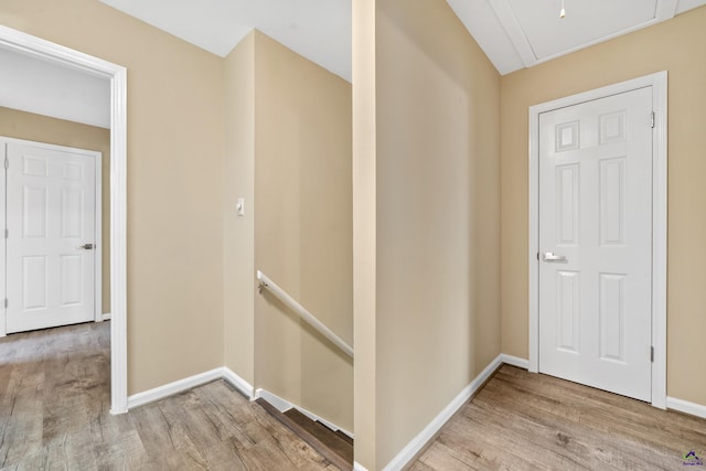 corridor featuring baseboards, an upstairs landing, attic access, and wood finished floors