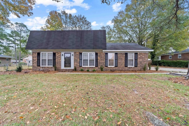 view of front facade with brick siding, a front yard, and fence