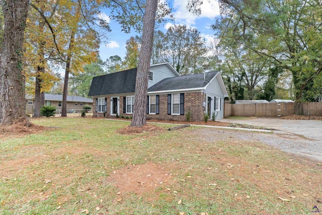 view of front facade with a front yard, fence, and brick siding