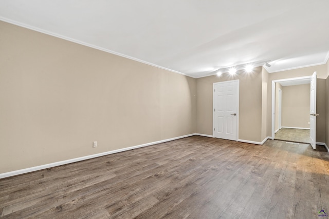 empty room featuring crown molding, baseboards, and wood finished floors