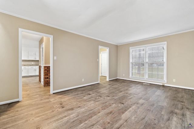 unfurnished room featuring crown molding, wood finished floors, and baseboards