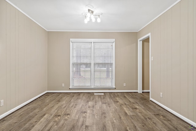 unfurnished room featuring ornamental molding, baseboards, and wood finished floors