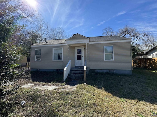 view of front of property with fence, roof with shingles, a front yard, and entry steps