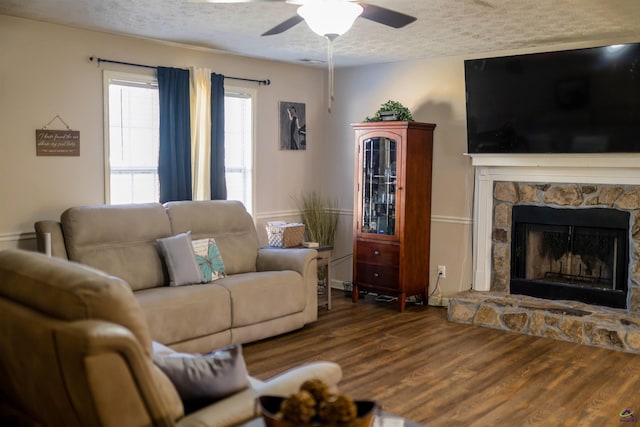 living room featuring a fireplace, a textured ceiling, ceiling fan, and wood finished floors