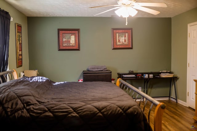 bedroom with ceiling fan, baseboards, a textured ceiling, and wood finished floors