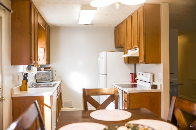 kitchen featuring under cabinet range hood, electric range, brown cabinets, and visible vents