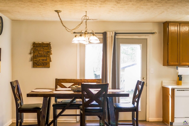 dining area with an inviting chandelier, baseboards, and a textured ceiling