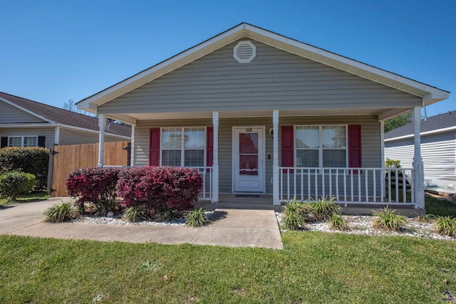 view of front of home with a porch, a front lawn, and fence