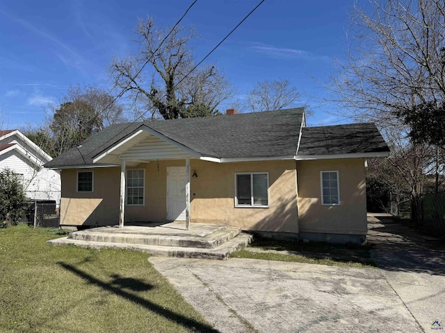 view of front of home with stucco siding, fence, a front yard, and a shingled roof