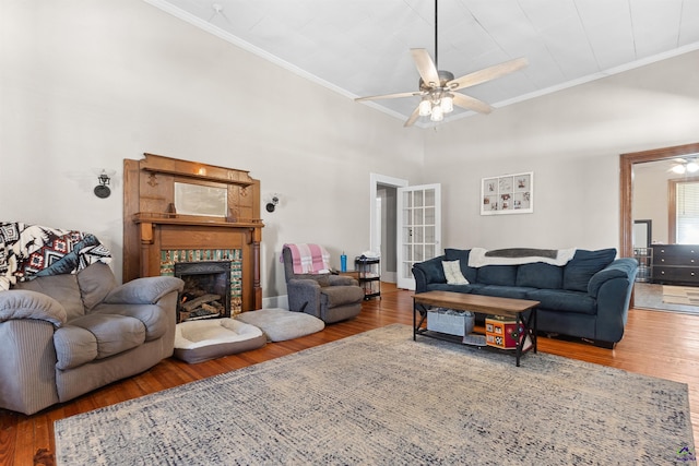 living area with ceiling fan, wood finished floors, ornamental molding, and a tile fireplace