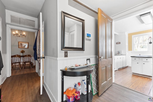 corridor featuring a wainscoted wall, a sink, and wood-type flooring