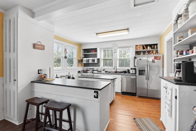 kitchen with open shelves, stainless steel appliances, dark countertops, and a peninsula