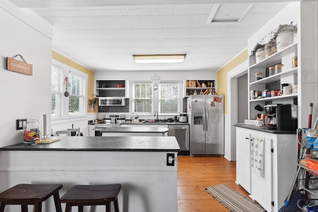 kitchen with open shelves, stainless steel appliances, and dark countertops