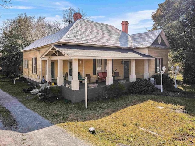 back of property with a lawn and a porch