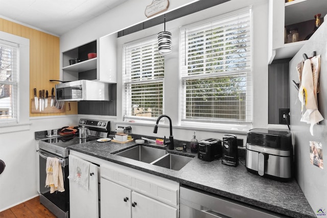 kitchen featuring dark countertops, a healthy amount of sunlight, appliances with stainless steel finishes, and a sink