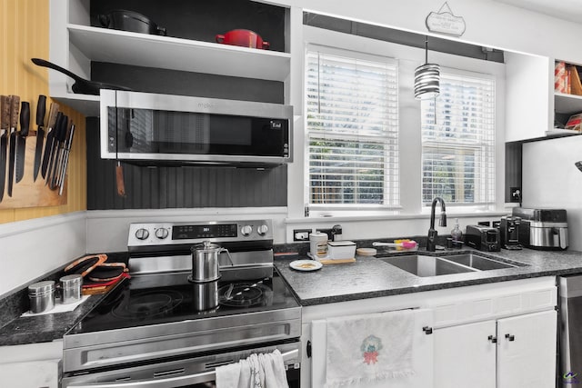 kitchen with open shelves, a sink, dark countertops, appliances with stainless steel finishes, and white cabinets