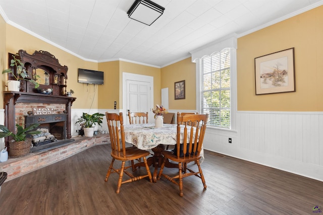 dining area featuring wainscoting, a fireplace, ornamental molding, and wood finished floors