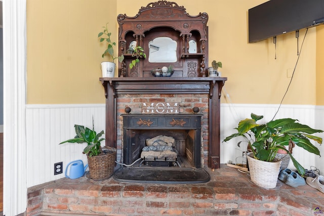 interior details featuring a fireplace and a wainscoted wall