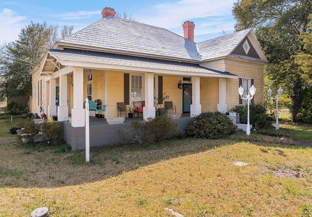 rear view of property featuring a yard, covered porch, and a chimney