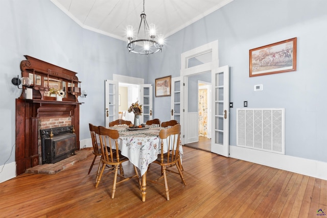 dining room with hardwood / wood-style flooring, a brick fireplace, visible vents, and ornamental molding