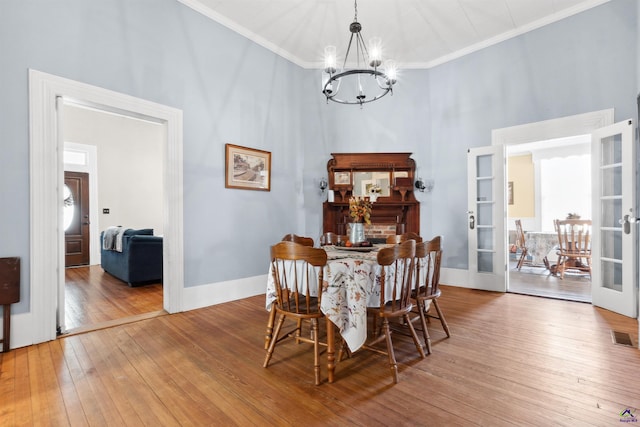 dining room featuring a chandelier, french doors, crown molding, and hardwood / wood-style flooring