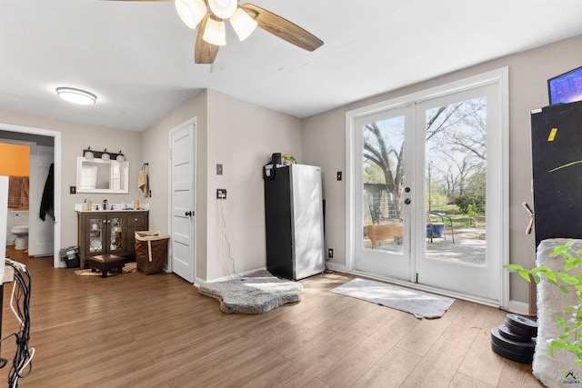 interior space with ceiling fan, french doors, baseboards, and wood finished floors