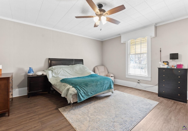 bedroom with baseboards, wood finished floors, a ceiling fan, and ornamental molding