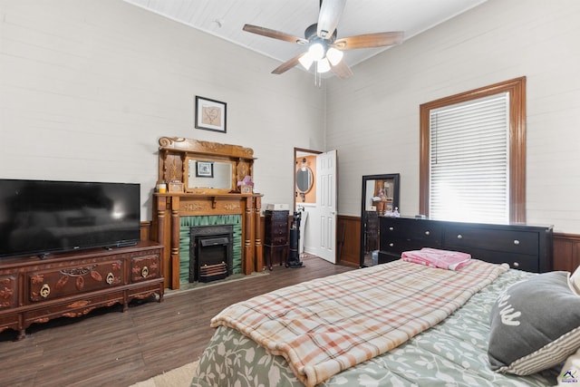 bedroom with a fireplace with flush hearth, wood finished floors, and a ceiling fan