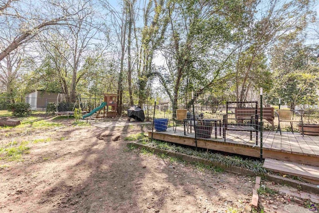 view of yard with a wooden deck, a playground, and fence