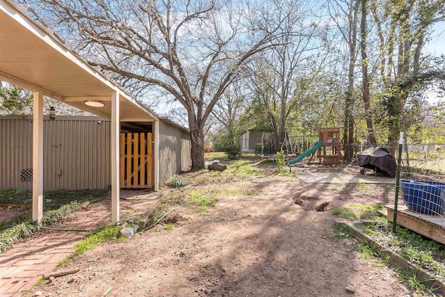 view of yard with an outbuilding, fence, and a playground