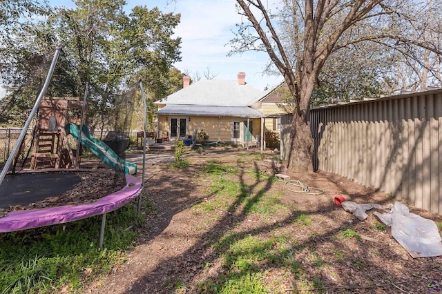 view of yard with a playground, a trampoline, and fence