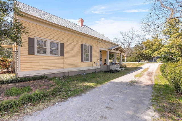 view of side of home featuring covered porch and a chimney