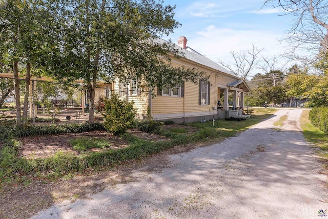 view of property exterior with a chimney and driveway