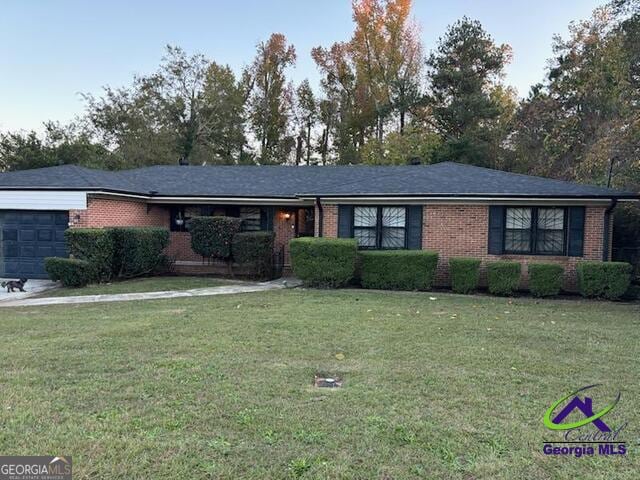 ranch-style house featuring brick siding, an attached garage, and a front lawn