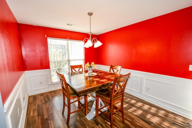 dining room with a wainscoted wall, wood finished floors, visible vents, and a chandelier