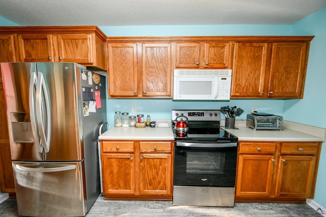 kitchen with light countertops, brown cabinets, and stainless steel appliances